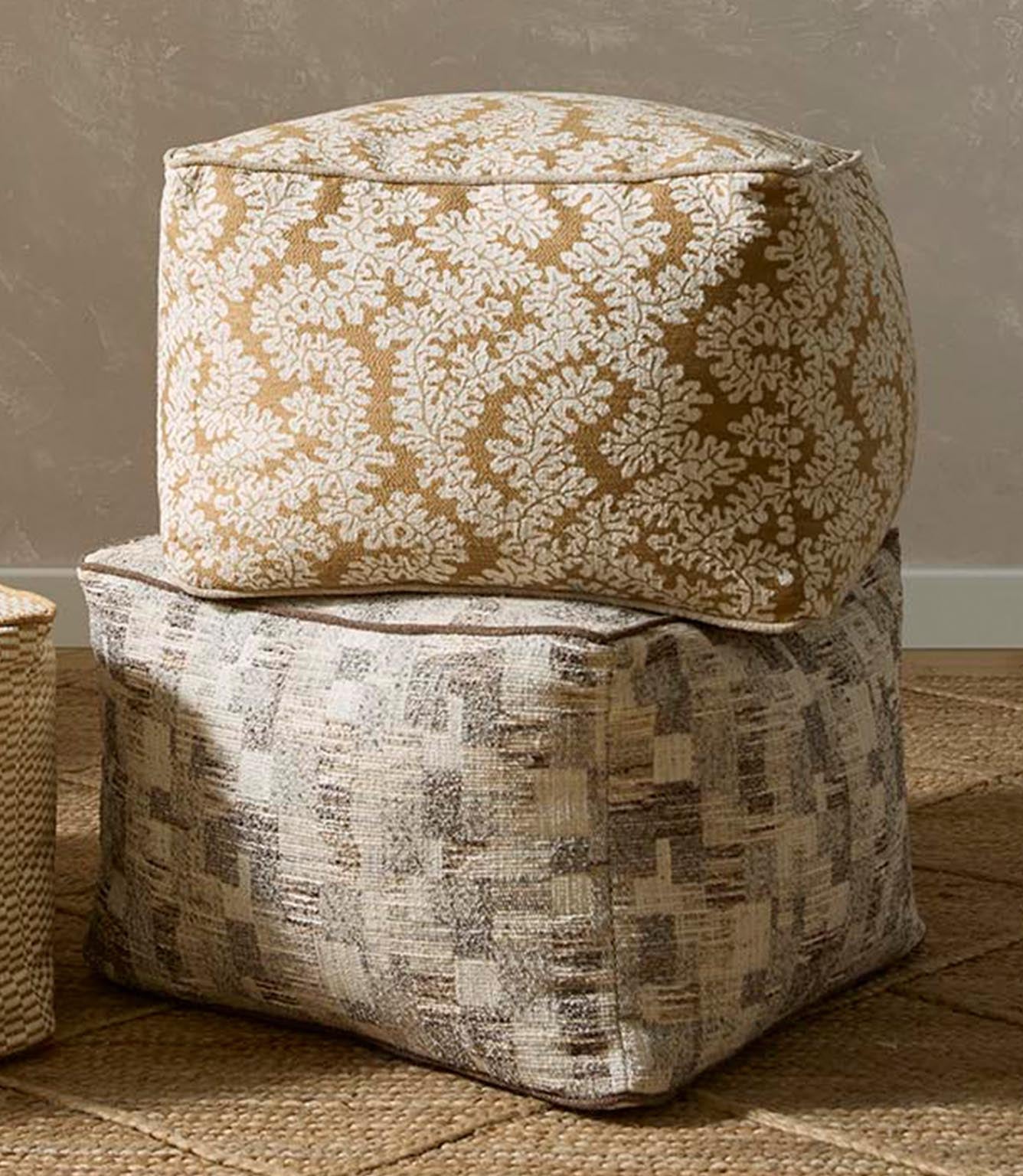 Upholstered ottomans featuring foliage patterned fabric in warm brown and ivory tones paired with a textured woven design in neutral shades.