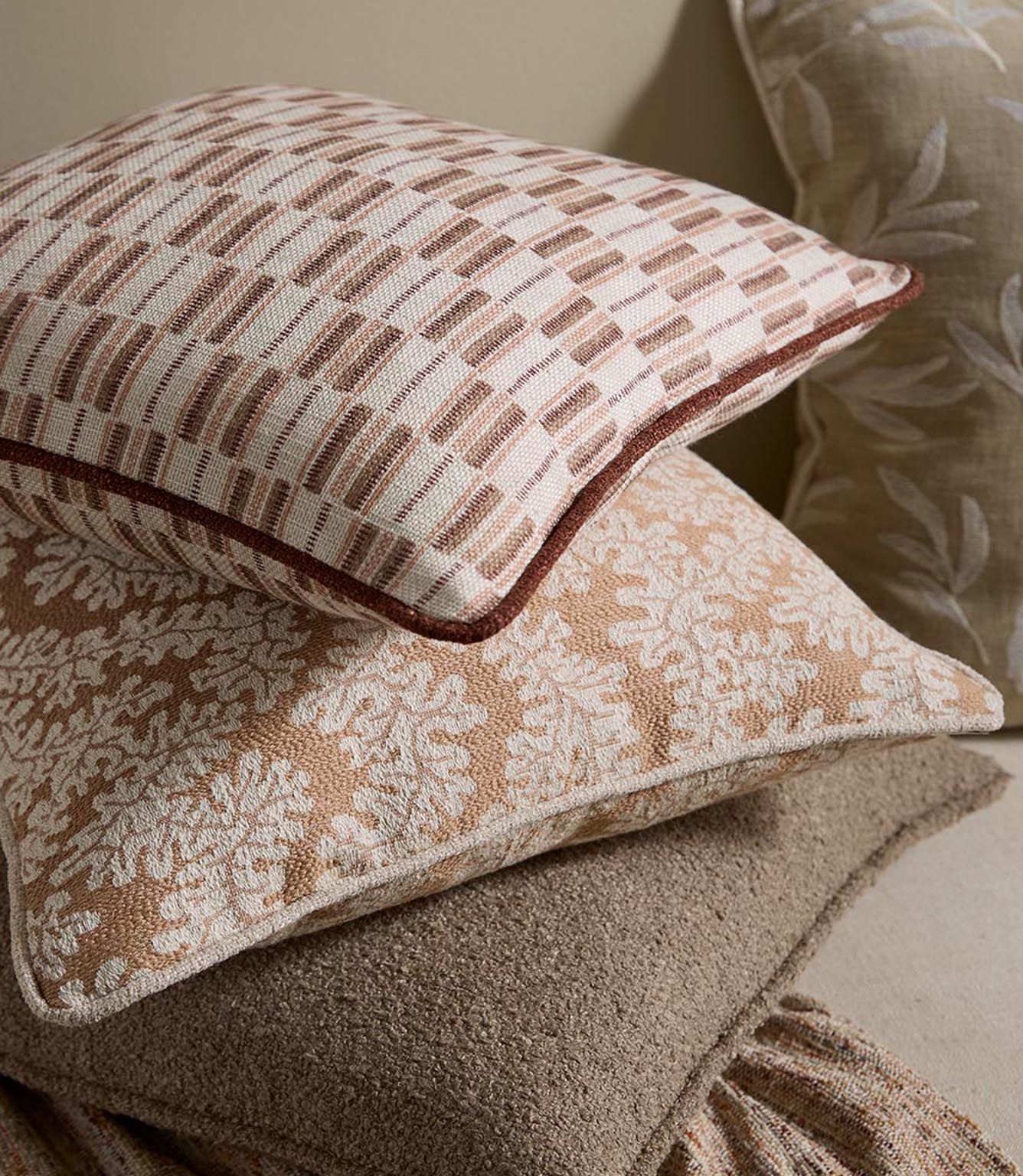 Styled cushions upholstered in the same terracotta stripe fabric, layered with coordinating neutral and patterned designs for a warm, relaxed interior look.