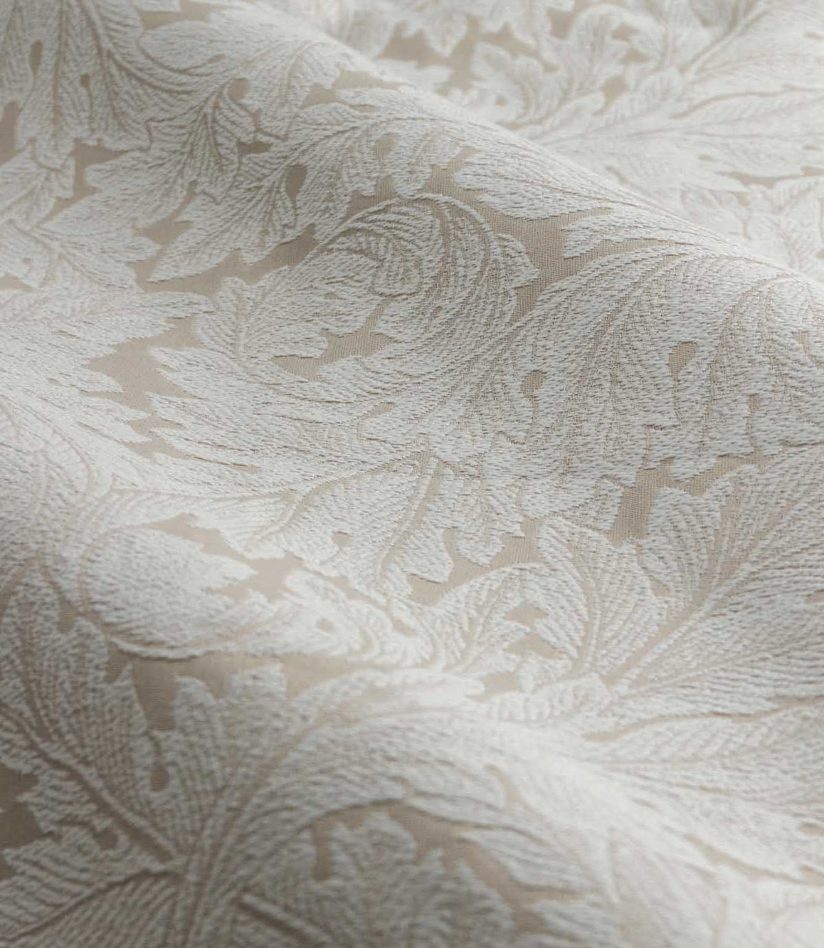 Close-up of Morris & Co Acanthus jacquard fabric in cream and warm beige, showing the raised woven texture and intricate scrolling acanthus leaf pattern.