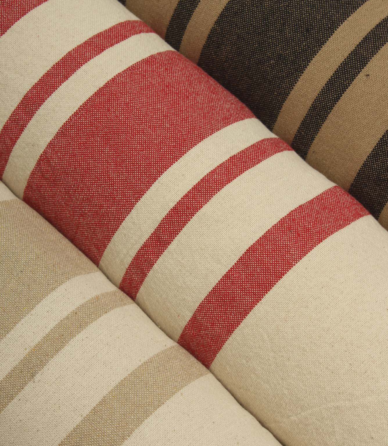 Angled display of coordinating striped fabrics featuring warm earthy shades, textured woven finishes, and timeless stripe patterns suitable for upholstery and curtains.