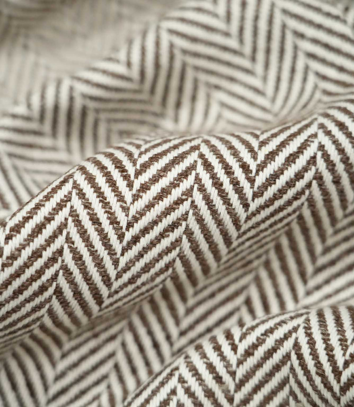 Macro close-up of draped Bampton Bison herringbone fabric, highlighting the individual woven fibres, raised texture and detailed chocolate brown and off-white chevron design.
