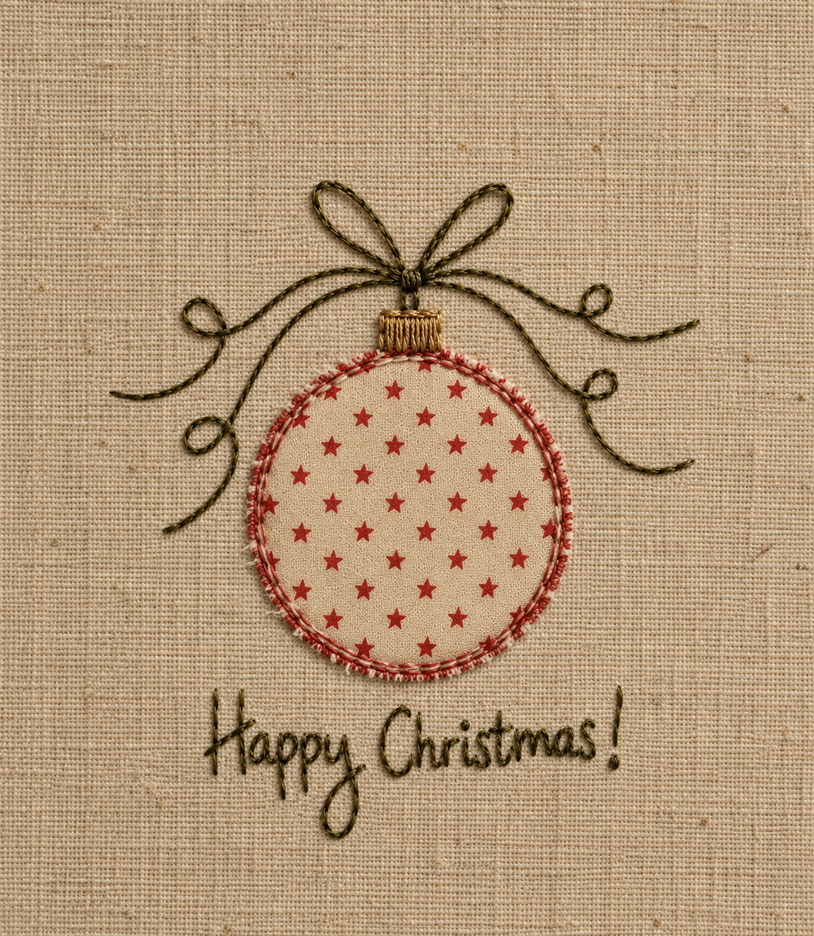A close-up of a fabric ornament design on a beige woven background, featuring a round ornament with small red stars, a red stitched border, a dark brown bow above it, and the words 'Happy Christmas!' stitched below.