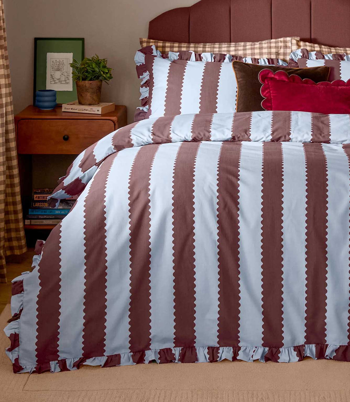 Birdie Stripe Ruffle duvet cover set in chocolate brown and pale blue, styled on a bed with matching striped pillowcases, ruffled edges and layered decorative cushions.