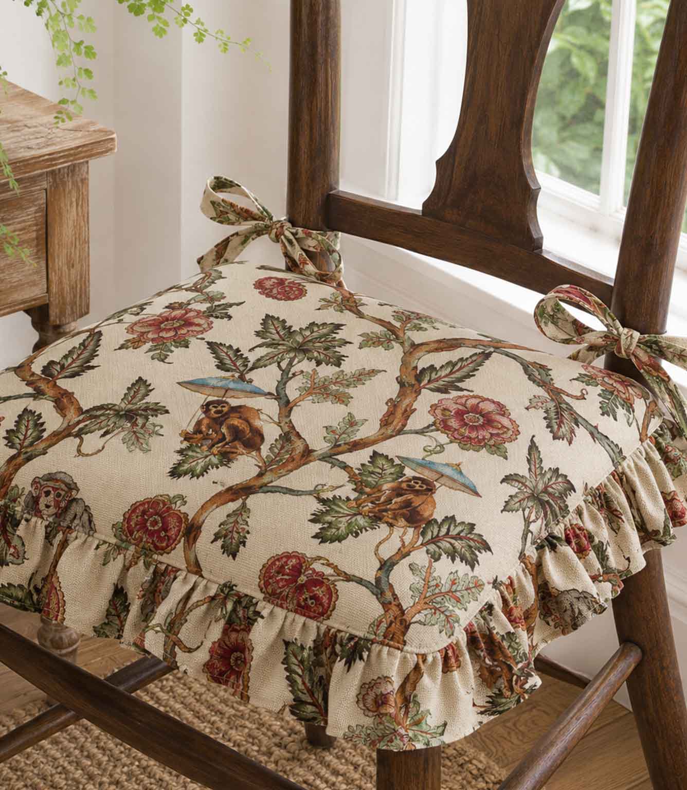 Decorative chair cushion with monkey and floral pattern on a wooden chair.