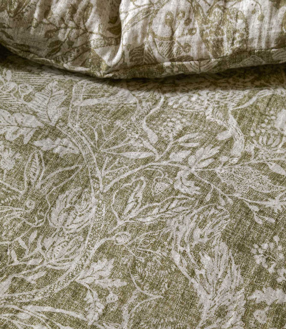 Detailed close-up of Voyage Maison Cademuir bedding in green and white, highlighting the intricate woodland design of birds, leaves and botanical motifs.