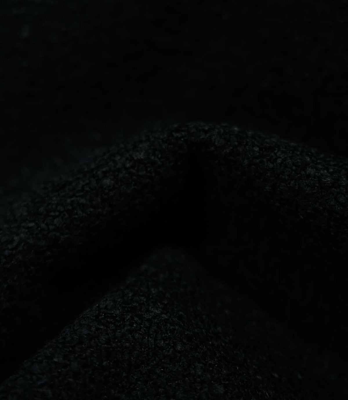 Macro detail of draped Case Bouclé Noir fabric, highlighting the dense black bouclé texture and softly structured folds of the upholstery material.