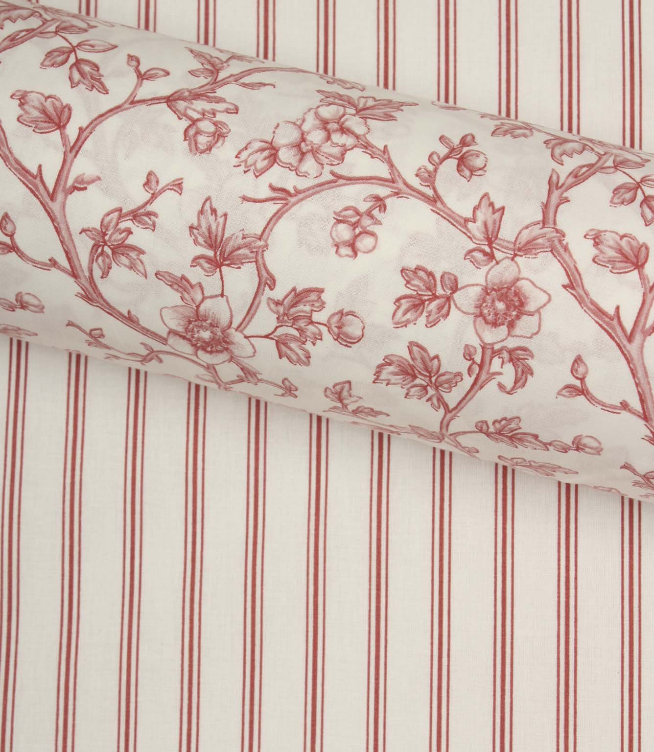 Red ticking stripe fabric paired with a coordinating floral fabric roll, styled to showcase complementary country-inspired designs.