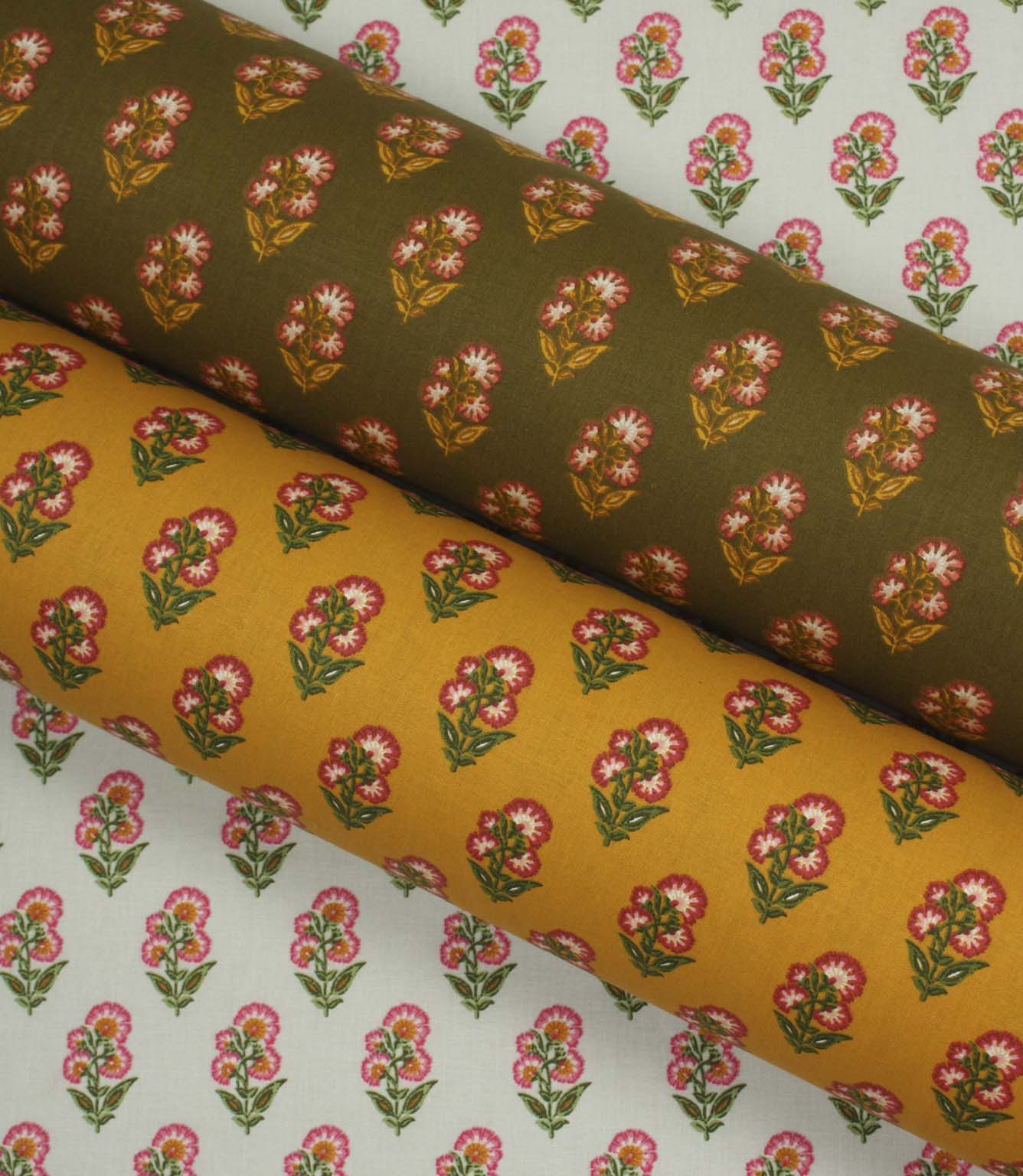 Coordinating botanical fabrics in soft ivory, warm ochre, and olive tones, each printed with small pink floral sprigs in a neat repeating pattern.