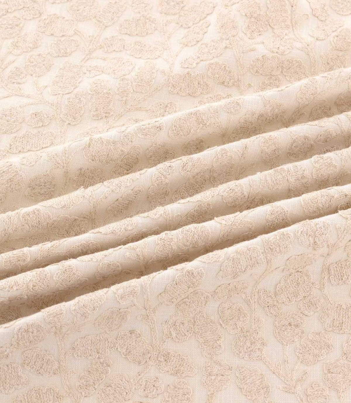 Gardiner Oyster fabric draped in gentle folds, highlighting the subtle beige botanical embroidery, raised leaf detailing and soft ivory background.