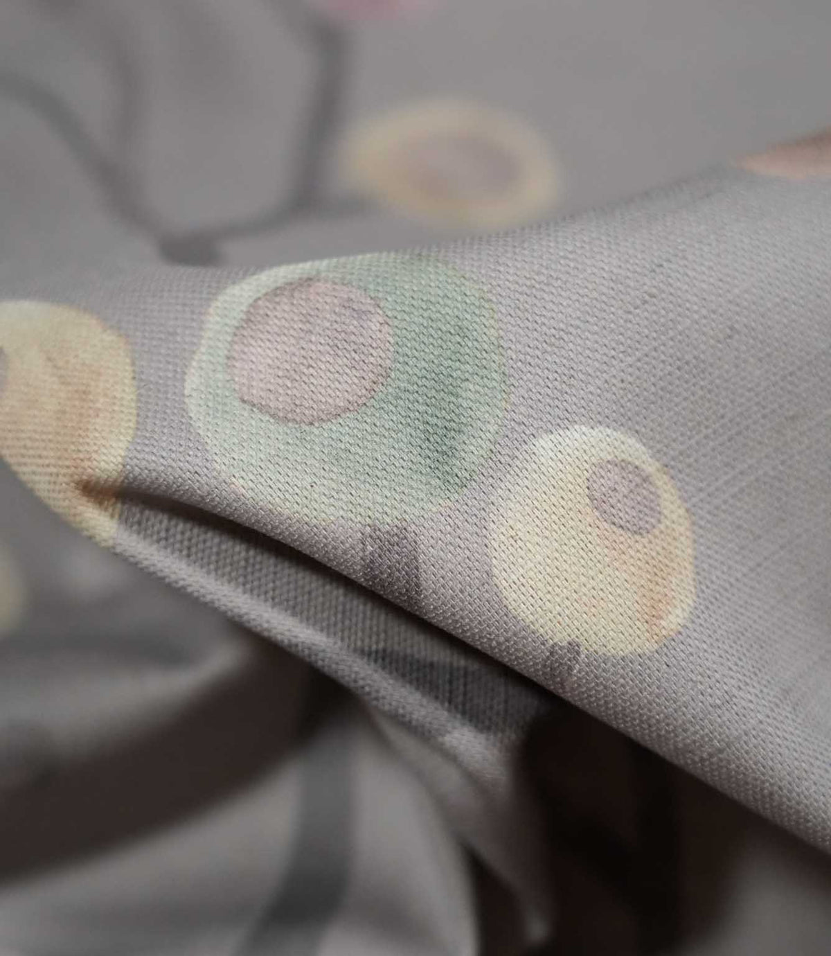 Detailed close-up of Ichiyo fabric showing the fine woven texture, soft grey background and delicate mint green and pale yellow circular botanical motifs.
