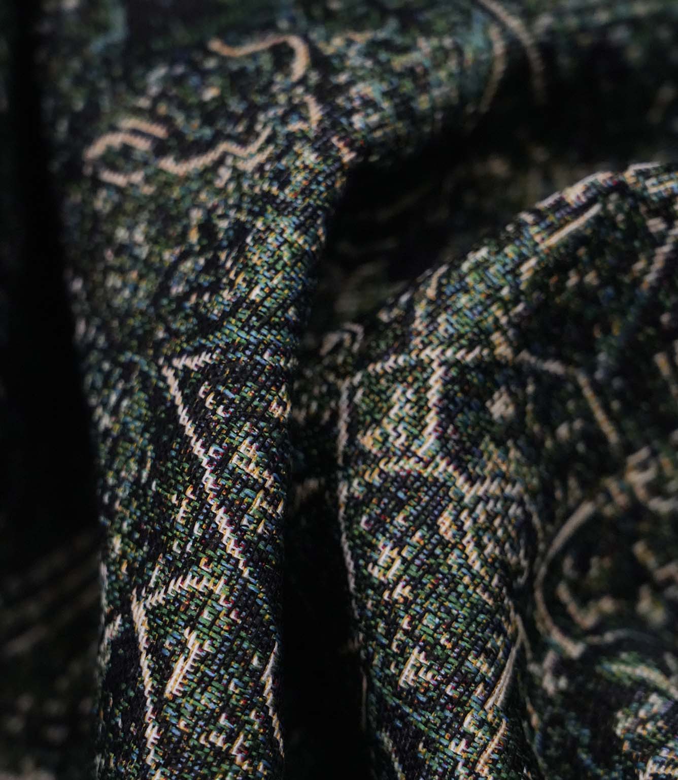 Close-up of green Keshan tapestry upholstery fabric showing the intricate woven texture and antique-inspired Persian motif.