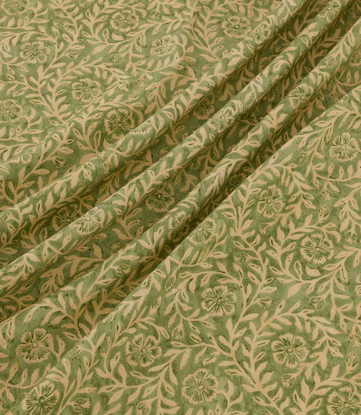 Manorville Kelp fabric arranged in soft, flowing folds, showcasing its detailed beige floral and foliage pattern against a natural moss green background, with delicate blossoms, intertwining stems and a subtly textured finish.