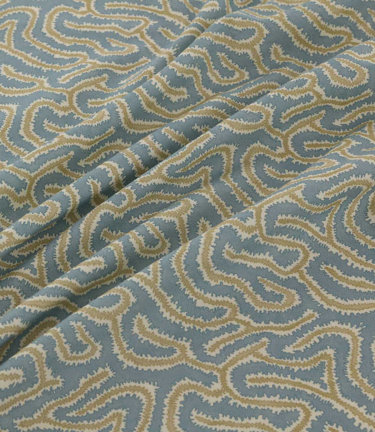Noyack Saltwater fabric arranged in soft, flowing folds, showcasing its muted duck egg blue background and distinctive abstract pattern of winding cream and warm beige lines, with textured edges and a repeating organic design.