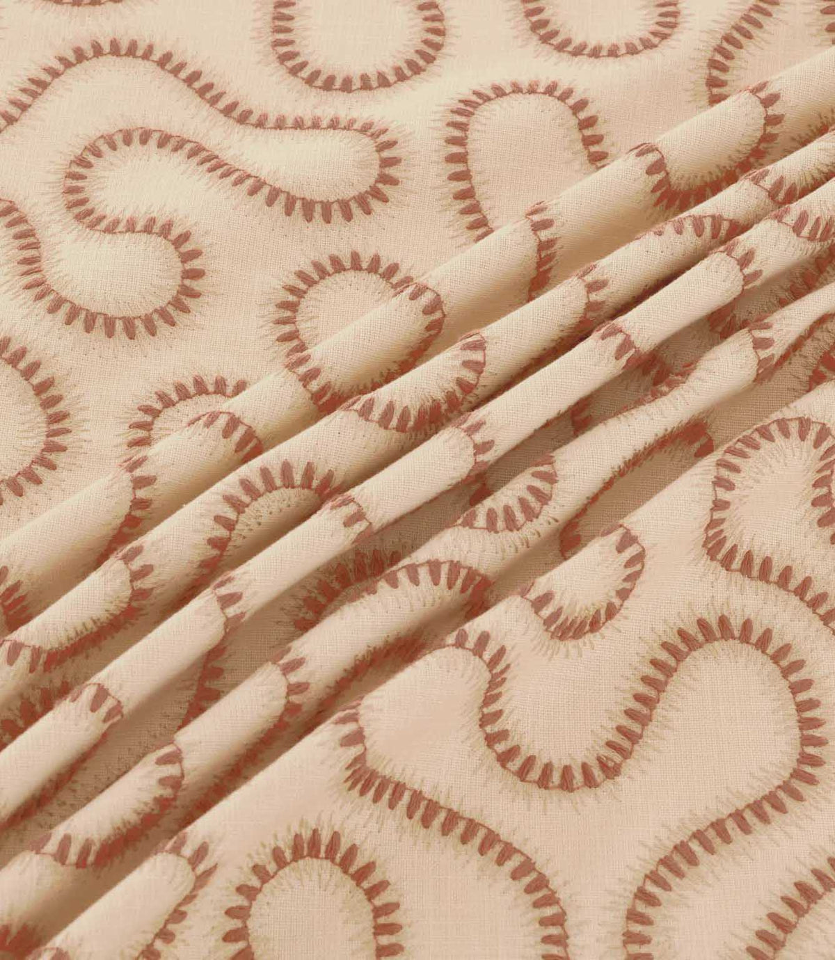 Close-up of Orient Coralee fabric draped in soft folds, showing terracotta embroidered wavy lines on a cream woven base and detailed stitching.