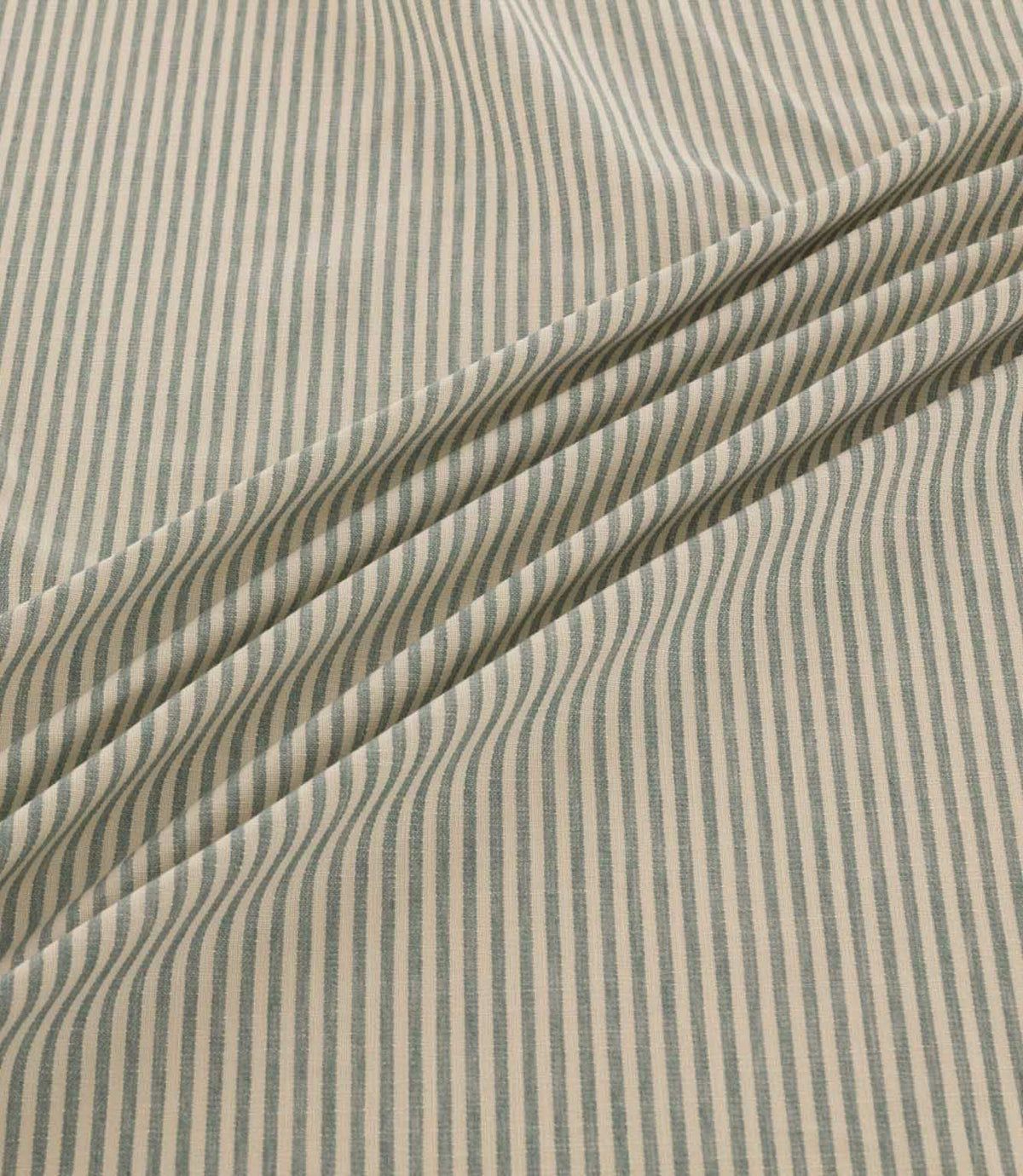 Shoreham Saltwater fabric arranged in soft diagonal folds, showcasing its delicate blue-grey and natural cream vertical stripes, textured woven finish and natural drape.