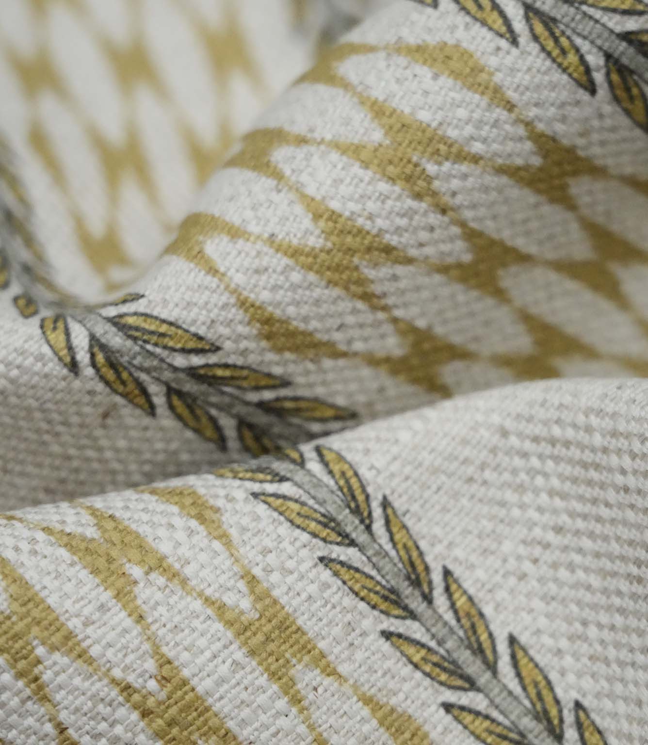 Close-up detail of Varese Gold upholstery fabric showing the woven texture and stylised foliage border.