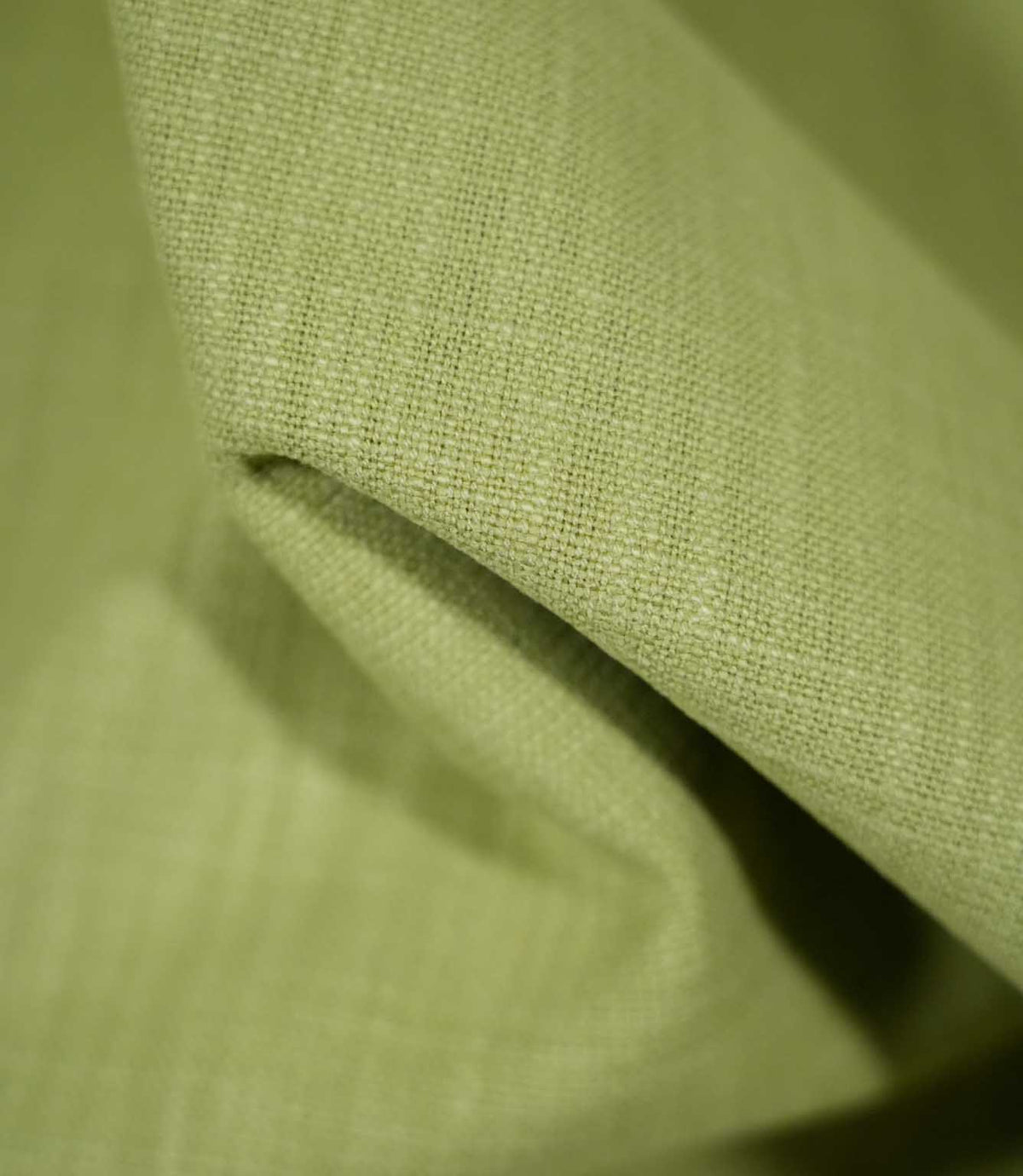 Macro photograph of Waverley Celery fabric draped into a soft fold, showing the detailed green woven threads and textured finish.