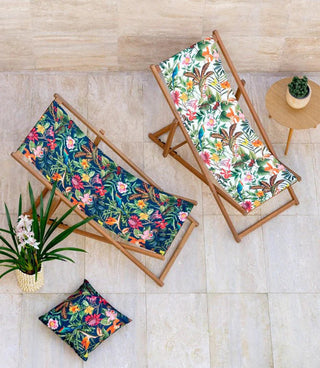 A bright, airy living room filled with warm summer sunlight. Sheer linen curtains hang loosely around open glass doors, gently diffusing the light and moving slightly as if in a breeze. Beyond the doors, a lush green garden stretches into the distance. In