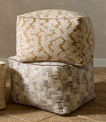 Upholstered ottomans featuring foliage patterned fabric in warm brown and ivory tones paired with a textured woven design in neutral shades.