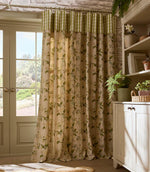 Country-style curtains in a soft botanical print with green leaves and delicate blossoms, finished with a green gingham header, hanging beside a glazed door in a light-filled room.