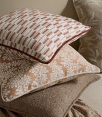 Styled cushions upholstered in the same terracotta stripe fabric, layered with coordinating neutral and patterned designs for a warm, relaxed interior look.