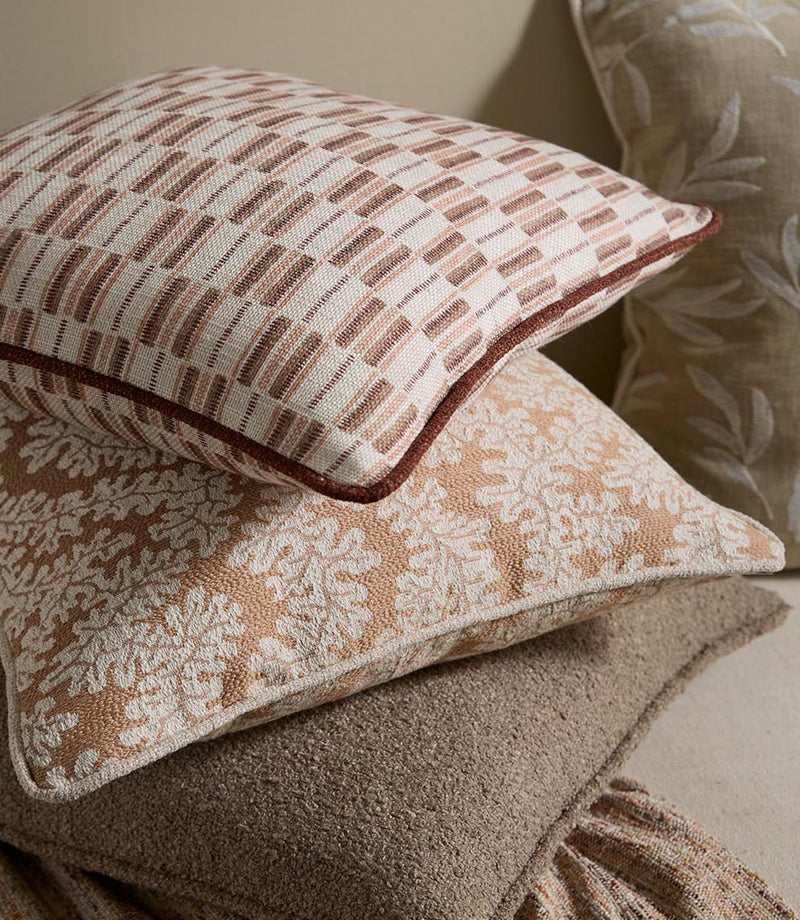 Styled cushions upholstered in the same terracotta stripe fabric, layered with coordinating neutral and patterned designs for a warm, relaxed interior look.
