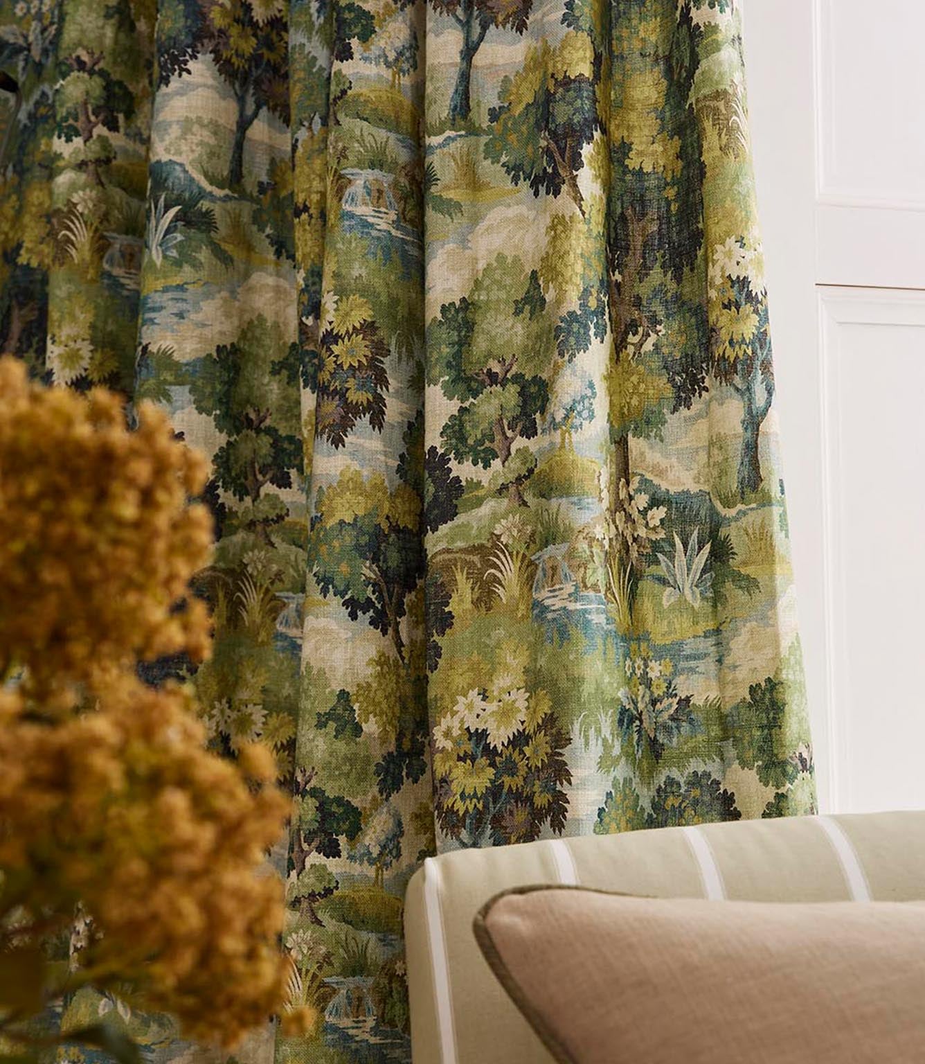 Close-up of draped curtains in a detailed pastoral landscape print, featuring trees, foliage, and soft greens and ochres in a painterly style.