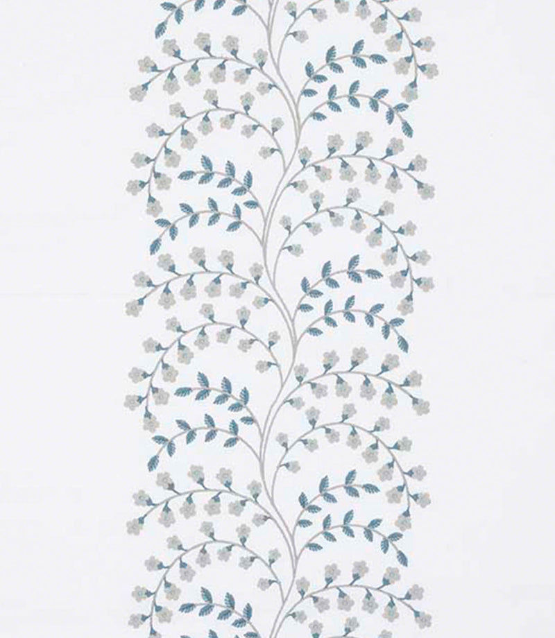 Close-up of designer embroidered foliage fabric featuring trailing stems with small blossoms in muted teal and soft grey on a warm off-white ground, highlighting texture and stitch definition.