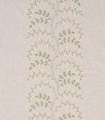 Close-up of designer embroidered fabric showing delicate vine pattern with small yellow flowers and light green leaves on a natural beige textured ground.
