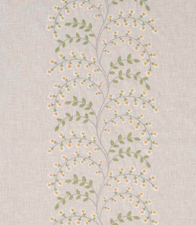 Close-up of designer embroidered fabric showing delicate vine pattern with small yellow flowers and light green leaves on a natural beige textured ground.