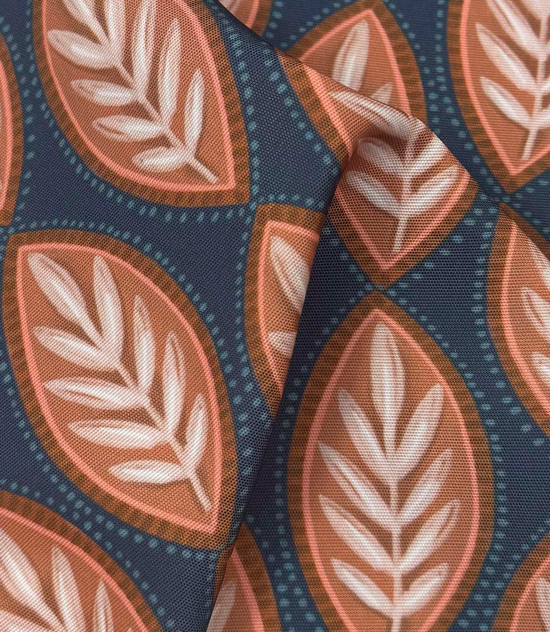Draped Amber Canopy outdoor fabric displaying textured woven foliage design in muted coral, brown, ivory, and deep blue tones.