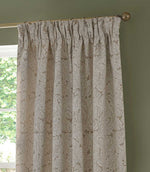 Morris & Co Acanthus jacquard curtain in cream and warm beige, showing the gathered pencil pleat heading and detailed woven leaf pattern against a green wall.
