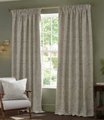 Pair of full-length Morris & Co Acanthus jacquard curtains in cream and warm beige framing a tall window, styled in a traditional living room with green walls and wooden furniture.