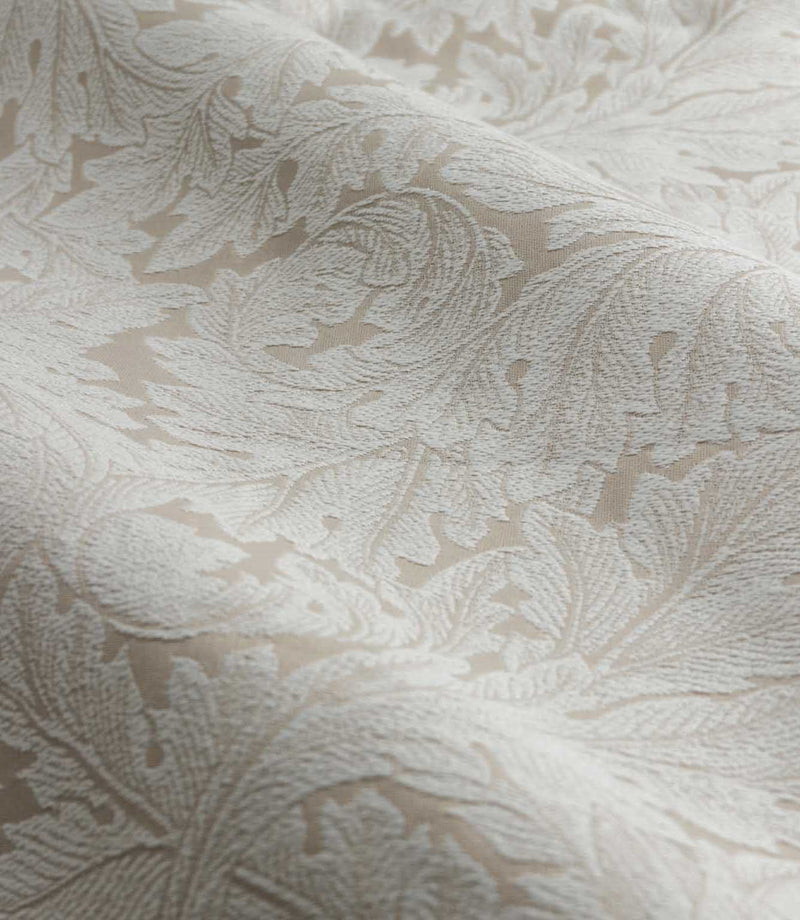 Close-up of Morris & Co Acanthus jacquard fabric in cream and warm beige, showing the raised woven texture and intricate scrolling acanthus leaf pattern.