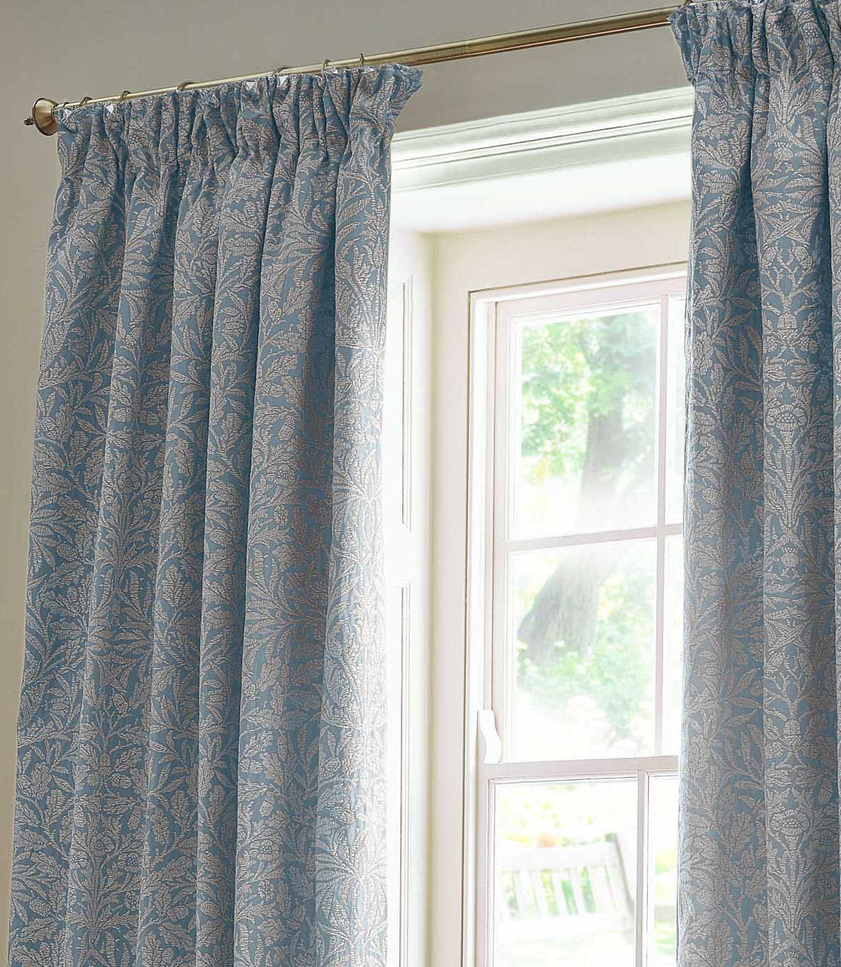 Close view of Morris & Co Acorn jacquard curtains in Wedgwood blue and off-white, showing the gathered pencil pleat heading and detailed acorn and foliage pattern.