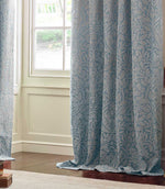 Full-length Morris & Co Acorn jacquard curtain in Wedgwood blue and off-white, draping onto a wooden floor beside a traditional panelled window.