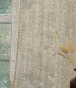 Close-up of Morris & Co Acorn sheer curtain fabric in soft cream and beige, showing the intricate acorn, leaf and floral pattern gently filtering natural light.