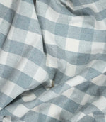 Aldsworth Check Haze fabric arranged in soft, flowing folds, showcasing its blue and white check pattern, woven texture and natural drape.