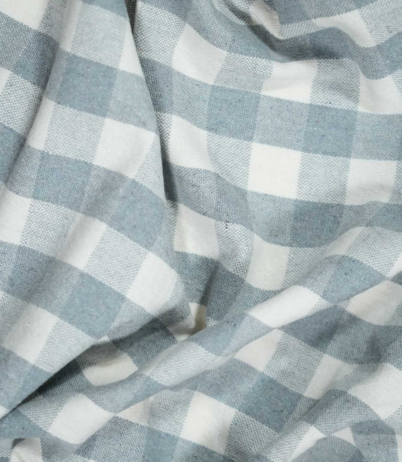 Aldsworth Check Haze fabric arranged in soft, flowing folds, showcasing its blue and white check pattern, woven texture and natural drape.
