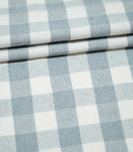 Layers of Aldsworth Check Haze fabric arranged in neat folds, showing the classic blue and white checks and subtle woven texture.