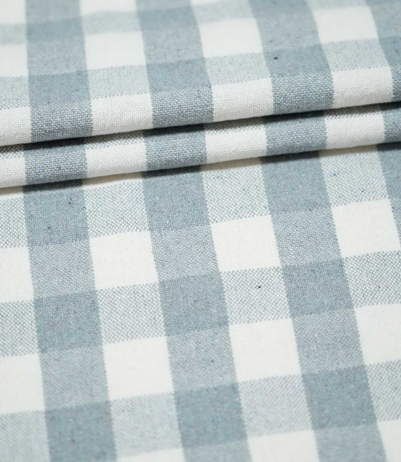 Layers of Aldsworth Check Haze fabric arranged in neat folds, showing the classic blue and white checks and subtle woven texture.