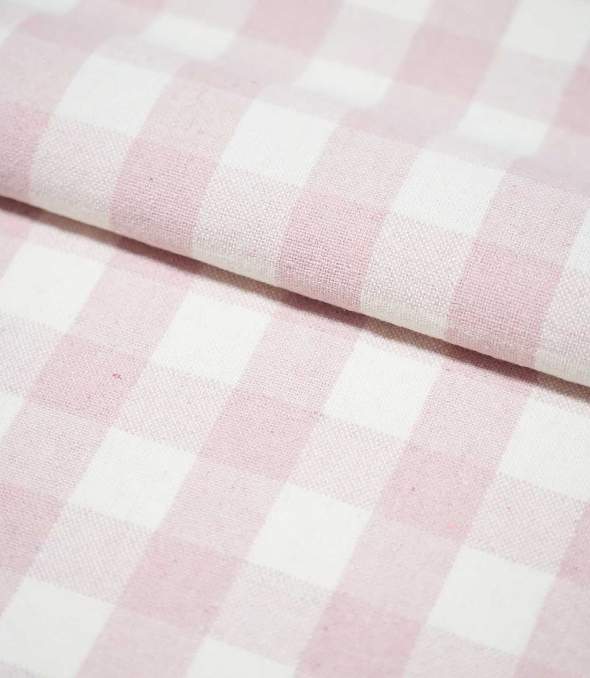 Folded Aldsworth Check Pink fabric displaying its repeating blush pink and white check pattern and subtly textured woven finish.
