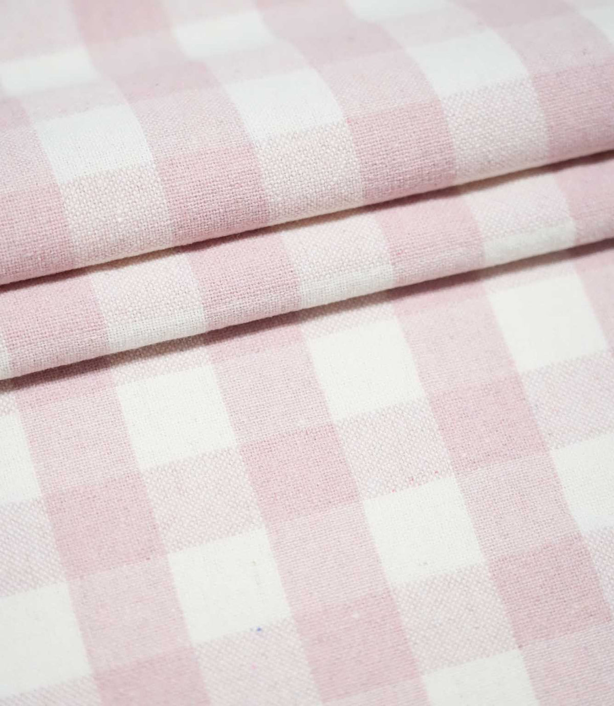 Layers of Aldsworth Check Pink fabric arranged in neat folds, highlighting the classic pink and white checks and woven texture.