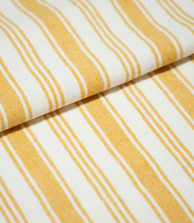 Folded Aldsworth Stripe Ochre fabric displaying its repeating golden ochre and off-white stripe pattern with fine woven detailing.