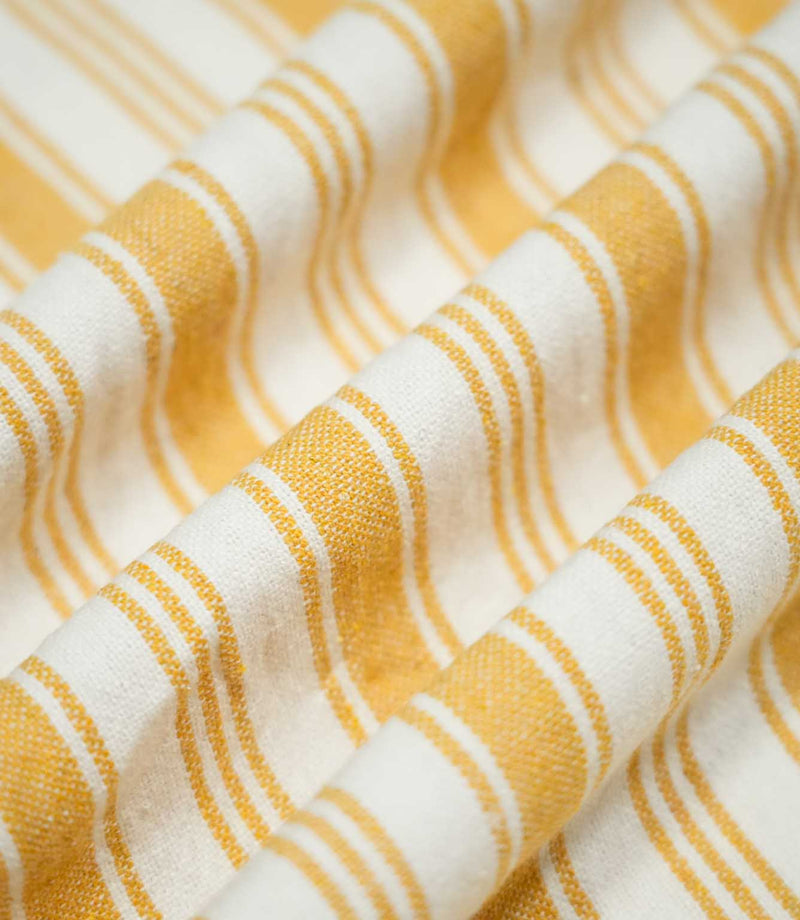 Aldsworth Stripe Ochre fabric arranged in soft, flowing folds, highlighting the alternating wide and narrow ochre stripes and natural drape.