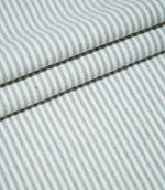 Aldsworth Ticking Haze fabric arranged in layered folds, showcasing its fine blue-grey and white striped pattern and textured woven surface.