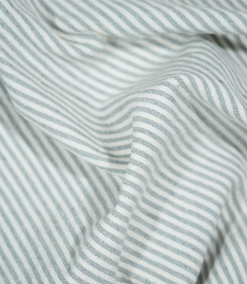 Aldsworth Ticking Haze fabric loosely draped in soft folds, displaying its traditional ticking stripe design and flexible woven texture.