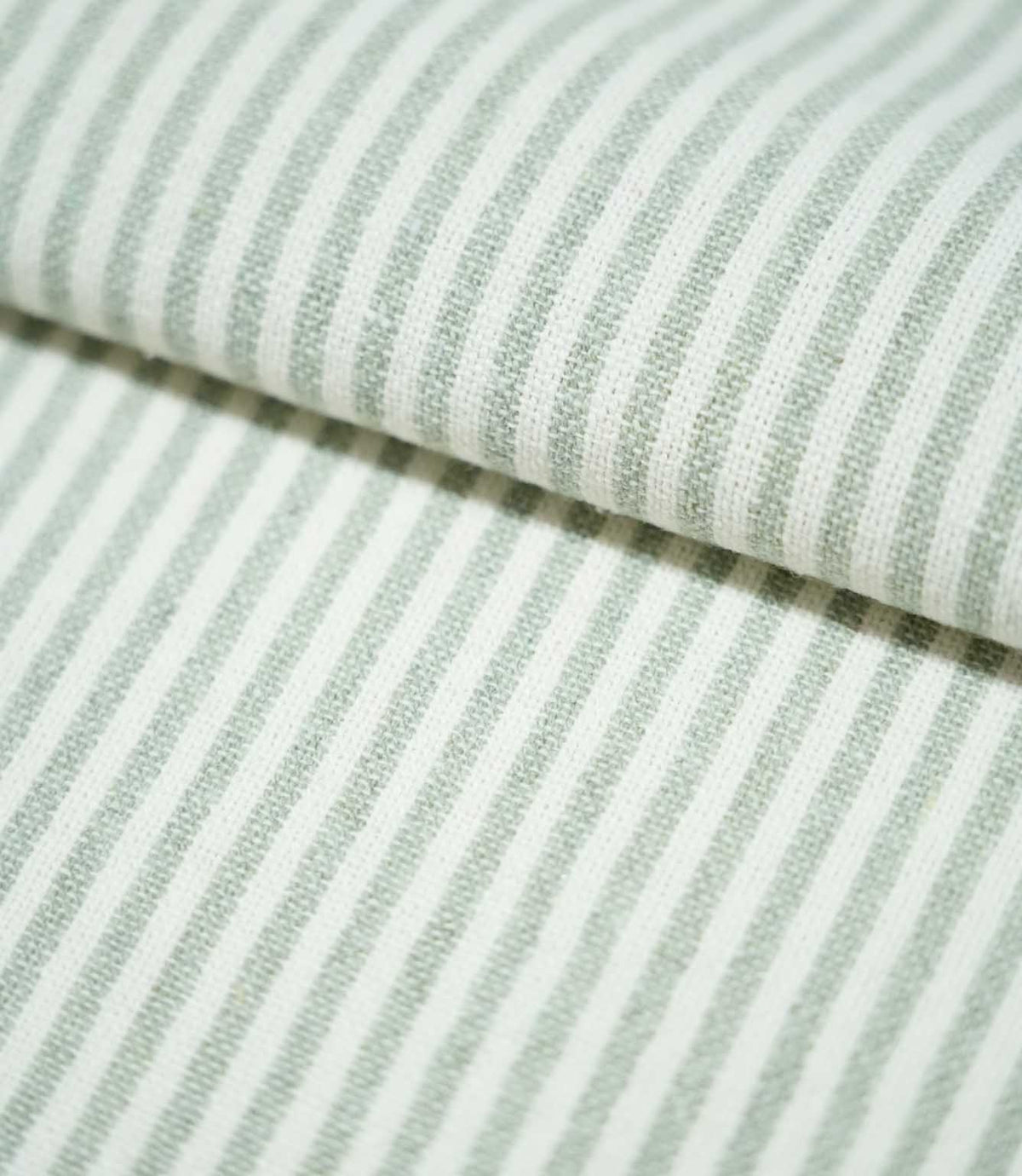Folded Aldsworth Ticking Mint fabric showing classic mint green and white ticking stripes, with a visible woven texture and soft muted colouring.