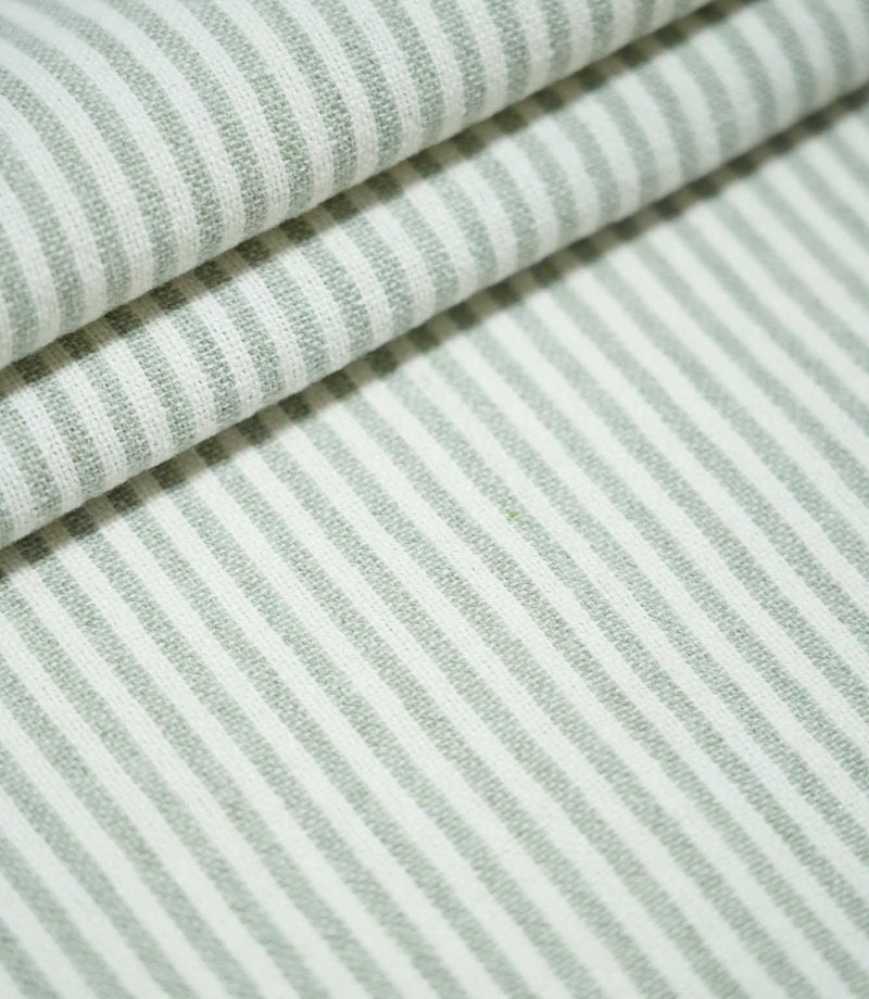 Aldsworth Ticking Mint fabric arranged in layered folds, showcasing its narrow green and white striped pattern and textured woven surface.