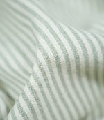 Detailed close-up of Aldsworth Ticking Mint fabric gathered into a raised fold, highlighting its pale green stripes, white detailing and textured weave.